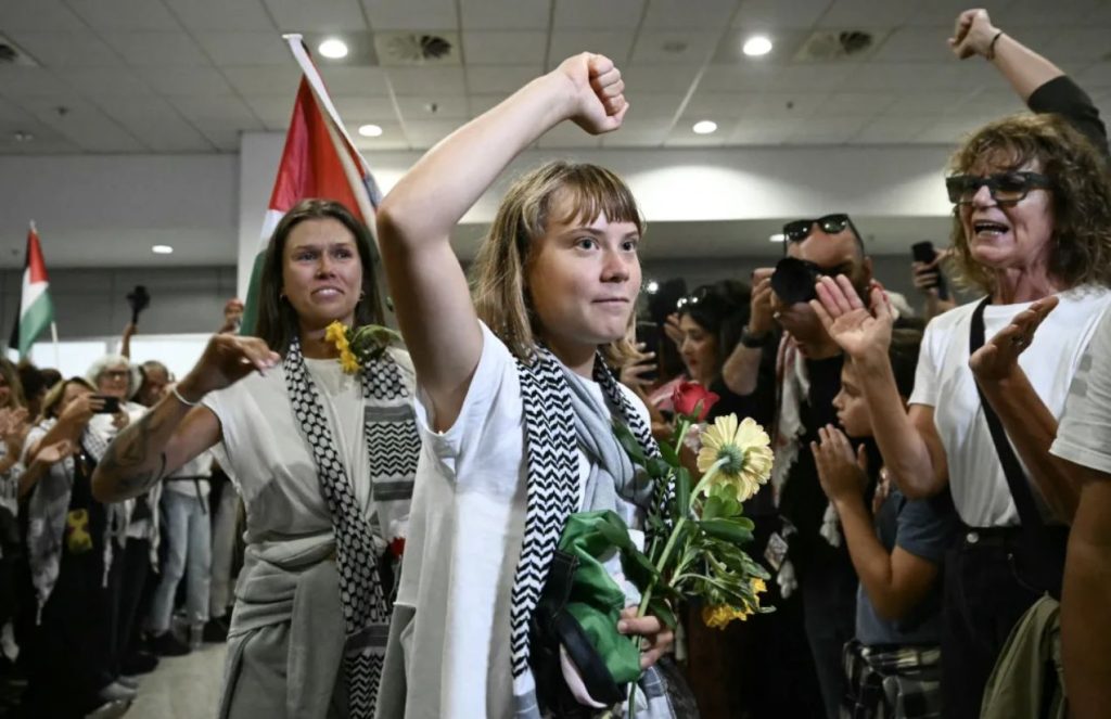 The activist arriving at an airport where many of her supporters are waiting for her, looking very happy