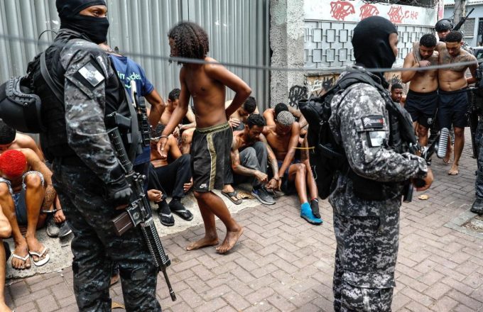 Armed men detaining several shirtless individuals believed to be members of favela gangs in Brazil