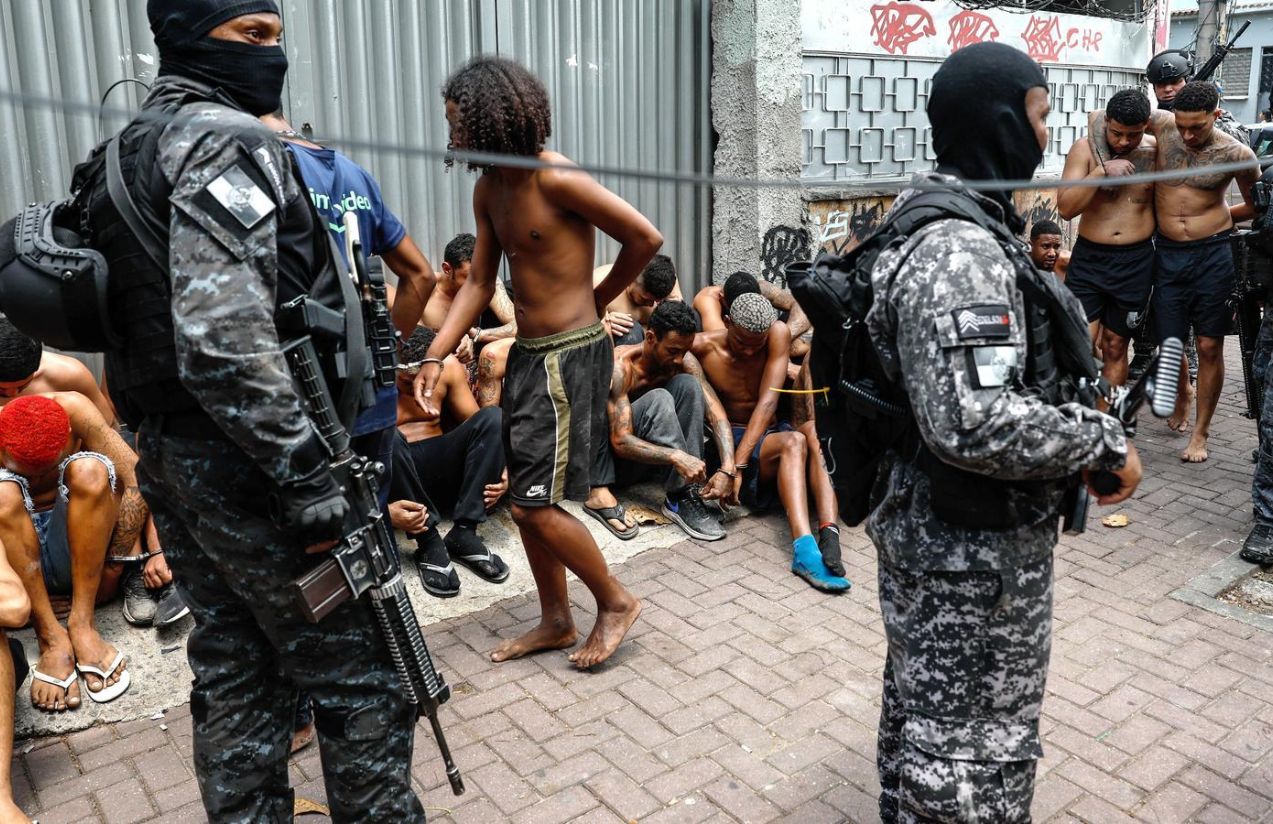 Rio de Janeiro faces Its most violent day: Massive police operation leaves at least 64 dead in favelas Armed men detaining several shirtless individuals believed to be members of favela gangs in Brazil