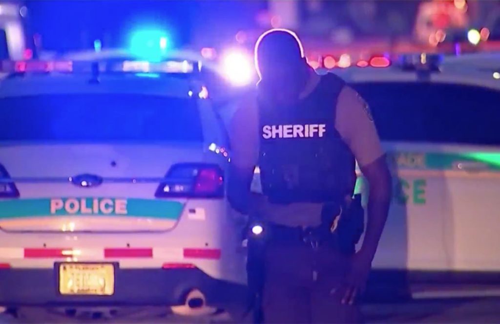 A Miami police officer walking down the street wearing his uniform and bulletproof vest