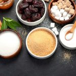 Several bowls of sugar, sweeteners, and other sweetening products placed on a wooden table