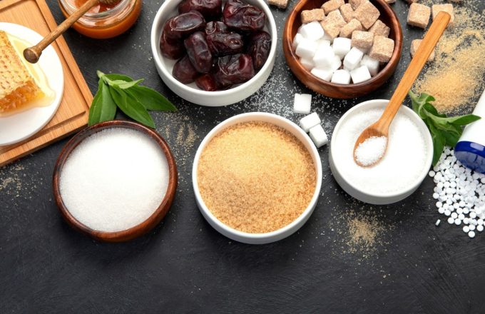 Sugar and sweeteners: hidden allies of liver damage Several bowls of sugar, sweeteners, and other sweetening products placed on a wooden table