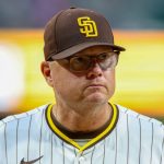 The experienced manager of the San Diego Padres wearing the team’s uniform with yellow details while walking across the field
