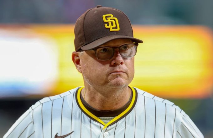 The experienced manager of the San Diego Padres wearing the team’s uniform with yellow details while walking across the field