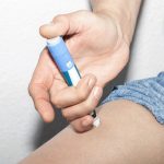 A person injecting some type of medication into their leg