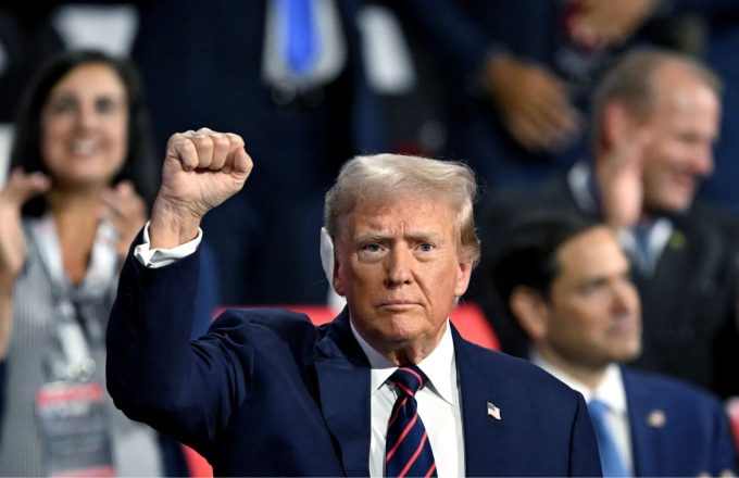 Donald Trump raising his right hand with a clenched fist during an interview, symbolizing strength and determination