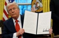 Trump holding up with both hands the signed document on this year’s new tariffs