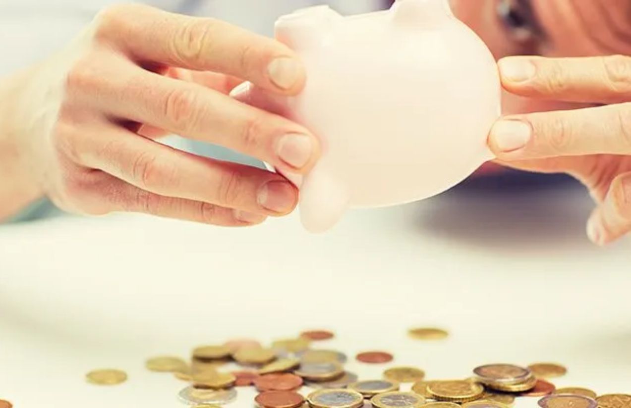 A person holding their piggy bank upside down to shake out their last savings