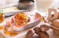 Several vitamin-D-rich foods placed on a table, fish, eggs, mushrooms, along with a cup filled with natural vitamin supplements