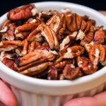 A person’s hands holding a bowl of pecan nuts that look delicious