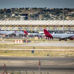 Several airplanes parked at an airport while passengers are boarding