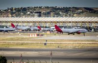 Several airplanes parked at an airport while passengers are boarding