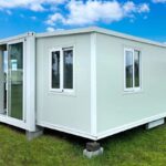A white Amazon prefab house placed on top of several stones to elevate it off the ground