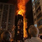 Many people watching from the ground as the buildings in Hong Kong burn.