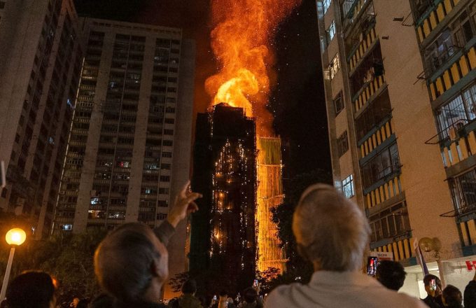 Many people watching from the ground as the buildings in Hong Kong burn.