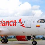 An Avianca airplane in its white and red colors parked at the airport waiting for passengers