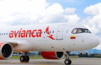 An Avianca airplane in its white and red colors parked at the airport waiting for passengers