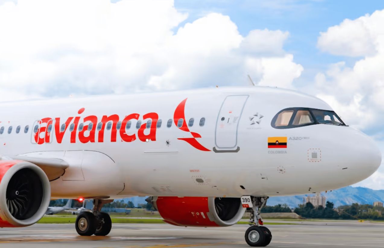 An Avianca airplane in its white and red colors parked at the airport waiting for passengers