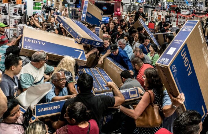A bunch of people crowded inside an electronics store, grabbing televisions however they can