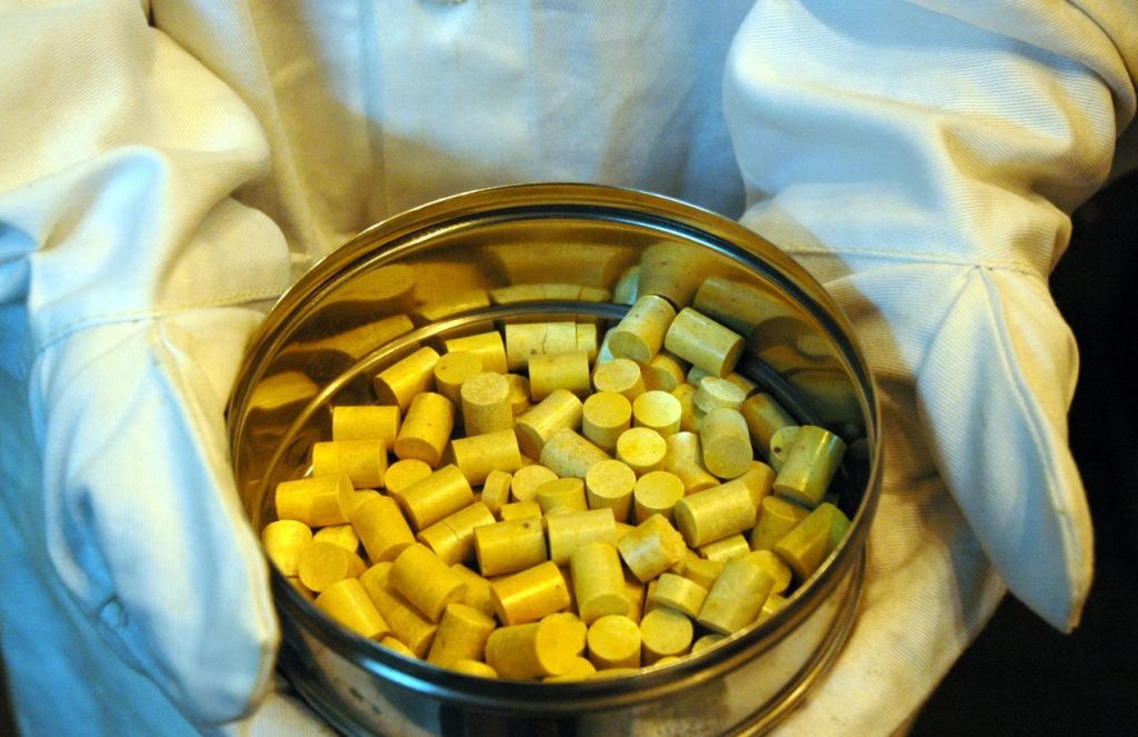 A scientist holding a jar of pure thorium while wearing a special suit