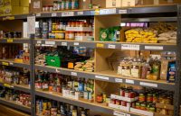 A food bank shelf filled with all kinds of canned goods and fresh fruits