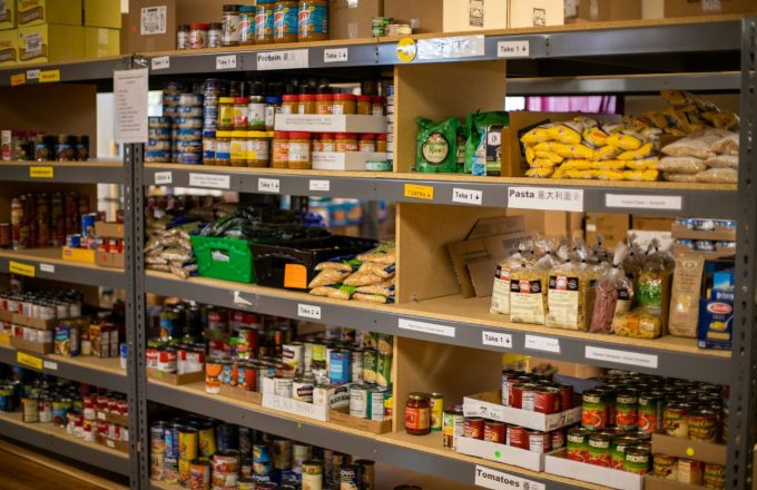 A food bank shelf filled with all kinds of canned goods and fresh fruits