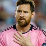 Messi wearing his pink Inter Miami uniform, watching from a distance at what is happening