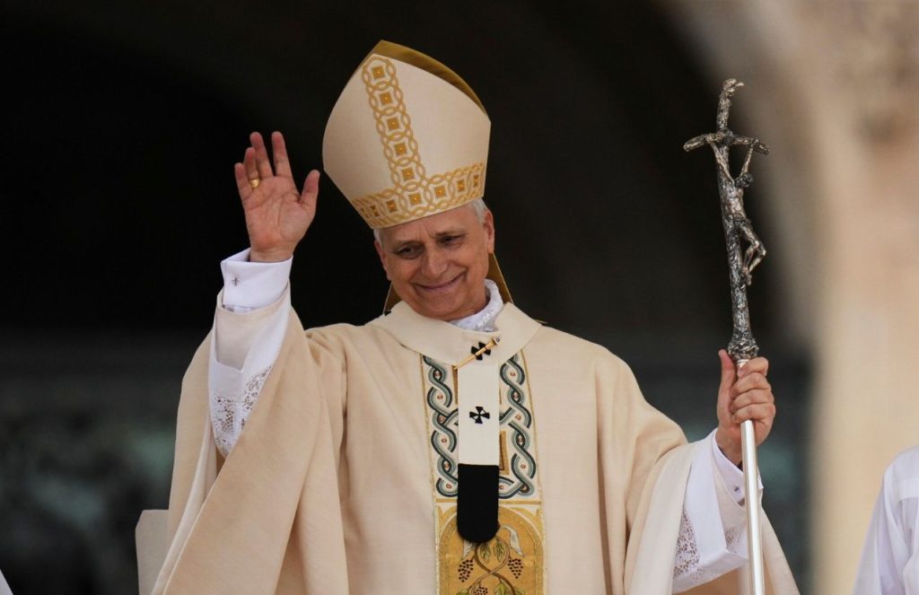 The pope greeting his audience while leaning out from one of the balconies of the Vatican