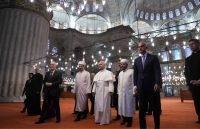 The Pope, dressed in white, walking down the steps of the Blue Mosque alongside Turkey’s religious leaders
