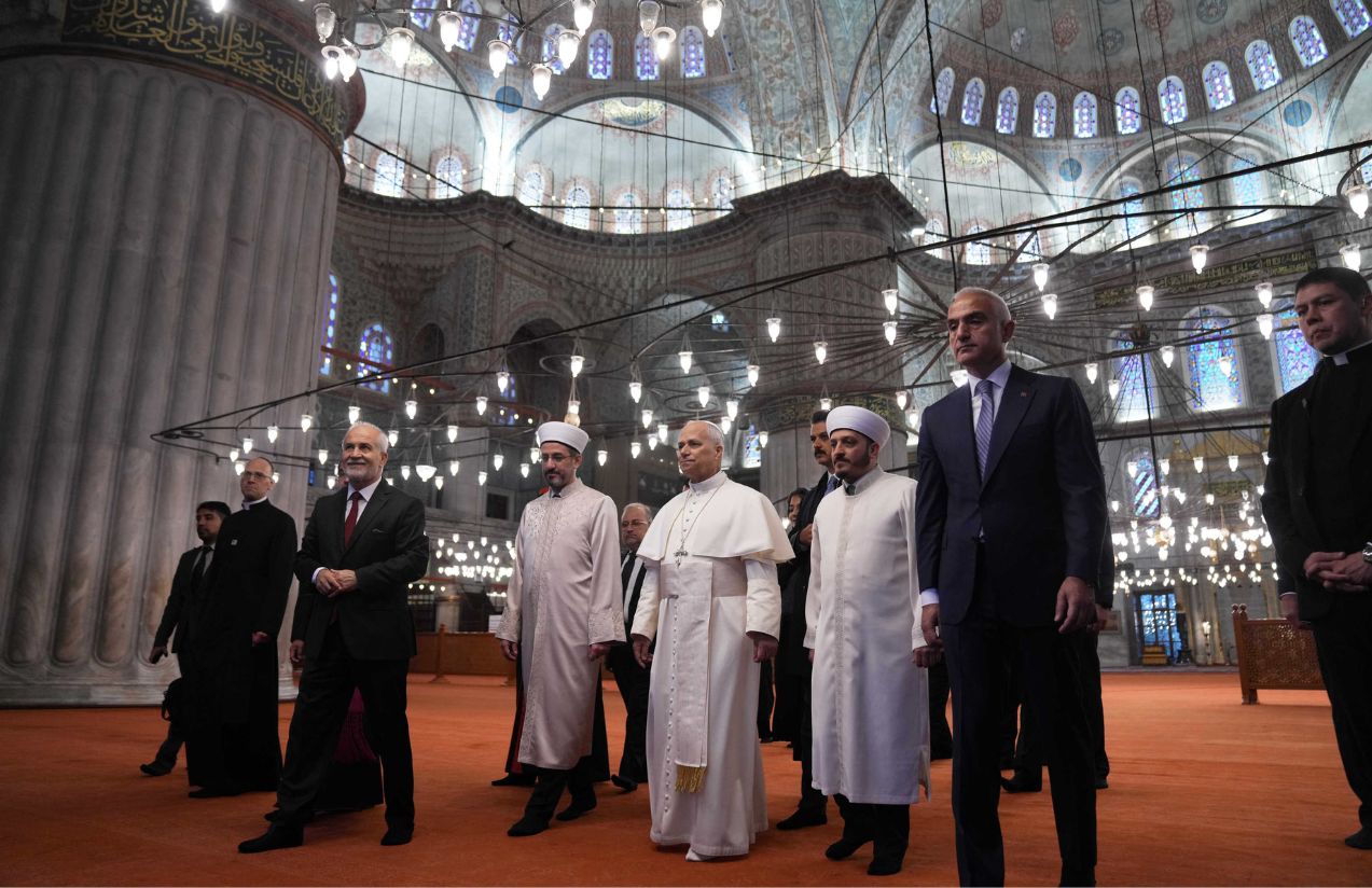 The Pope, dressed in white, walking down the steps of the Blue Mosque alongside Turkey’s religious leaders