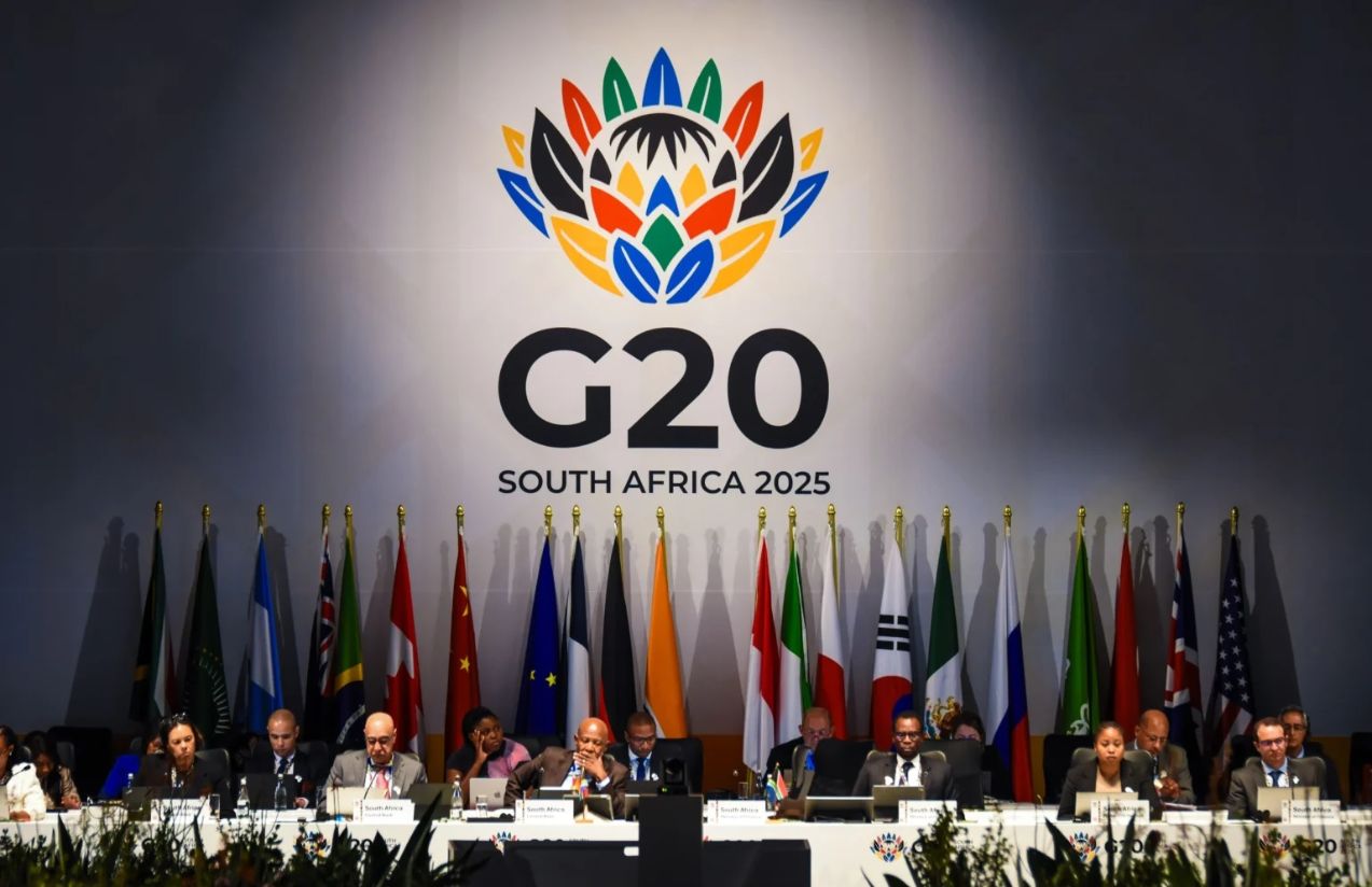 Several representatives of the G20 countries sitting at a table with their respective flags behind them