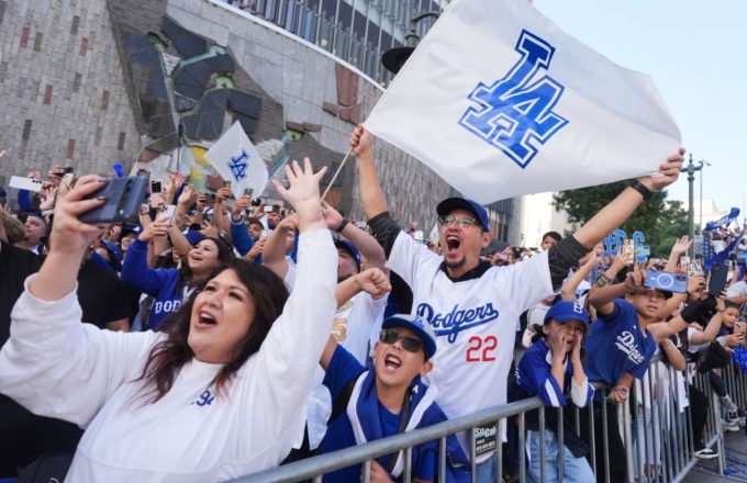Many Dodgers fans celebrating excitedly during the team’s parade after winning the baseball championship