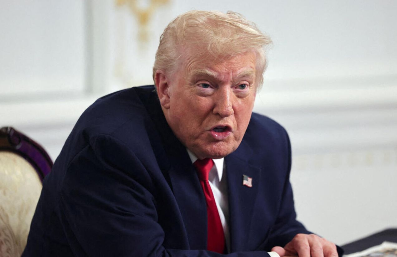 Donald Trump sitting in his office with a slightly angry expression while talking to someone