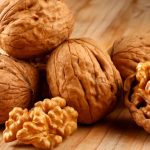 Several walnuts on a table, some with shells and others opened and ready to eat