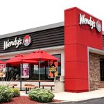 One of Wendy’s franchise locations featuring several outdoor tables with umbrellas and its signature red color tone