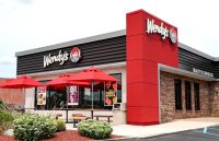 One of Wendy’s franchise locations featuring several outdoor tables with umbrellas and its signature red color tone