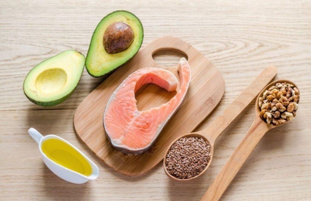 Some healthy foods such as fish, avocado, and various seeds placed on a table
