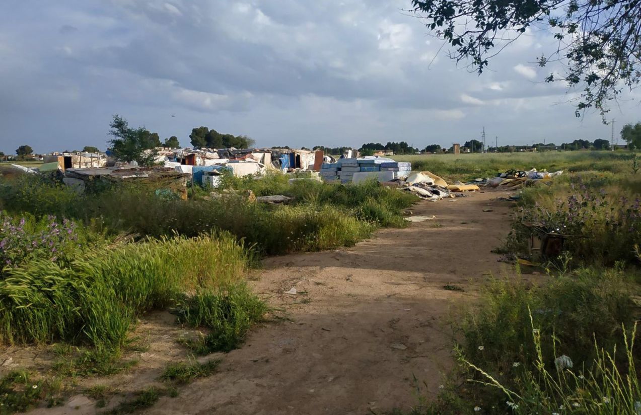 A panoramic view of a meadow in deplorable conditions, with lots of trash and a few people walking around
