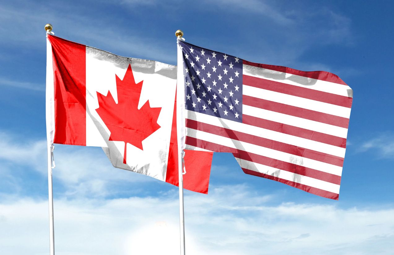 The flags of the United States and Canada waving in the wind