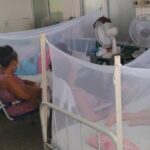 A person taking care of someone who is hospitalized on a stretcher due to dengue