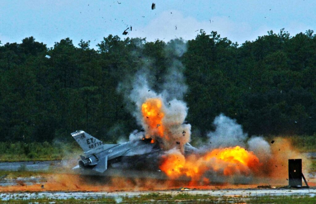 An F-16 crashed into the ground, surrounded by heavy flames and smoke