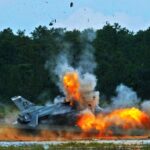 An F-16 crashed into the ground, surrounded by heavy flames and smoke