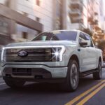 A Ford F-150 pickup truck driving through the streets with its lights on.