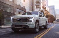 A Ford F-150 pickup truck driving through the streets with its lights on.