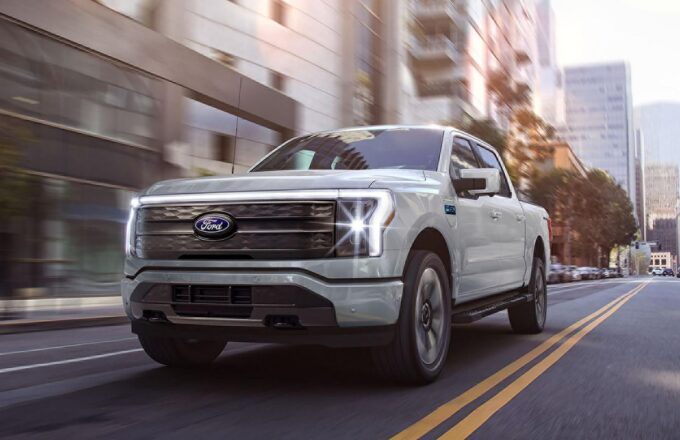 A Ford F-150 pickup truck driving through the streets with its lights on.