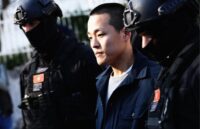 The cryptocurrency expert, Do Kwon, being escorted by two heavily armed officers as he is taken to jail
