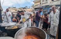 Several cooks stirring food to serve the residents of Gaza