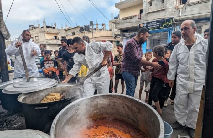 Several cooks stirring food to serve the residents of Gaza