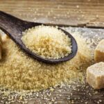 A spoonful of sugar and several sugar cubes on top of a wooden table
