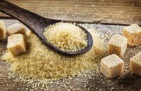 A spoonful of sugar and several sugar cubes on top of a wooden table